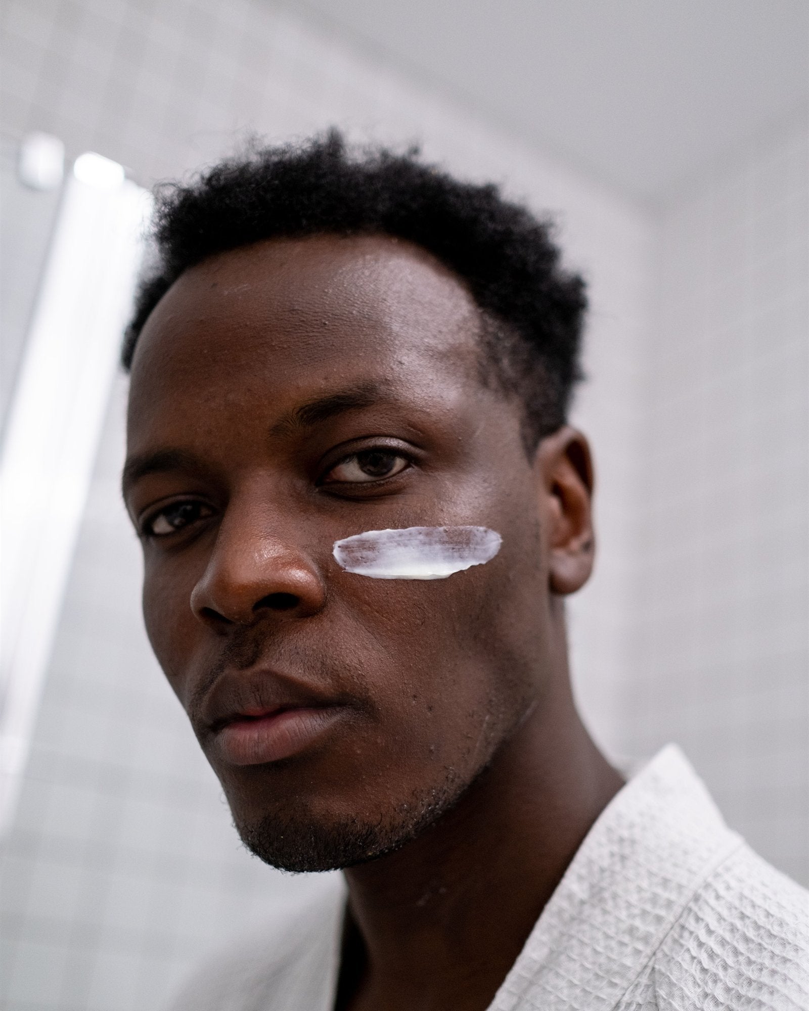Man with a stripe of cream on his cheek, ready to blend it in
